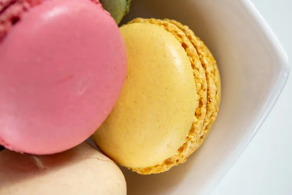 small multi-colored macaroons in a white plate on a white background