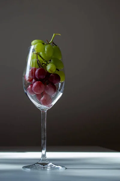 wine glass filled with green and red grapes