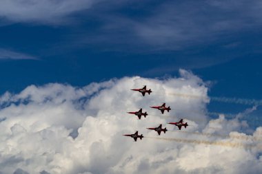 Six Swiss army planes against a blue sky and white clouds