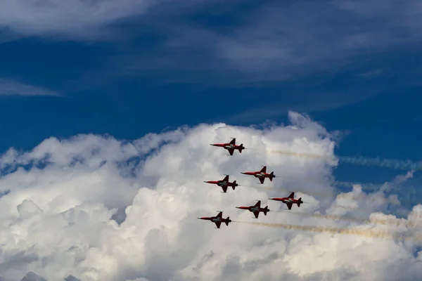 Six Swiss army planes against a blue sky and white clouds