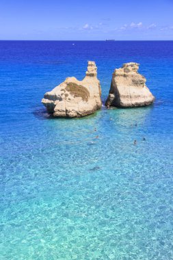 İtalya 'nın en güzel kıyısı Apulia' daki Torre Dell 'Orso Körfezi' dir. Salento 'nun tipik deniz manzarası: İki Kız Kardeş adı verilen iki yığının manzarası. Yaz zamanı: kristal berrak denizde yüzenler.