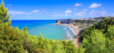 Peschici Körfezi, Apulia, İtalya: şehir manzarası ve kumlu plaj. Peschici, deniz kıyısındaki tatil beldeleri ile ünlü bir şehirdir. Bölgesi Gargano Ulusal Parkı 'na aittir..