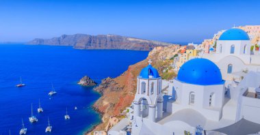 Santorini, Greece. Lovely view of Oia village with traditional famous blue domed church on the Caldera in the Aegean Sea. Traditional Cycladic architecture in white and blue.