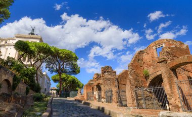 Antik Roma 'nın bir yolu olan Clivus Argentarius' un manzarası, antik asfaltın bir bölümünü ve onu çevreleyen tuğla odaların izlerini korur..