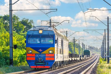 Dnepr, Ukrayna - 2021 yazı: Güçlü lokomotif DE1 tren istasyonuna bir yük treni çekiyor. Malların nakliyesi. Yaz havası. Gün batımı aydınlatma.