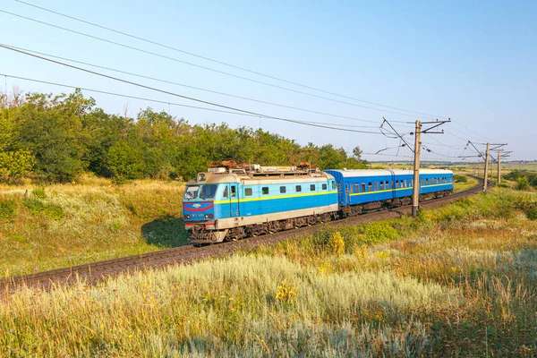 Inhuletler, Ukrayna - 2021 yazı: Elektrikli lokomotif yolcu vagonlarını Krivoy Rog 'dan tren istasyonuna çekiyor. Güneşli bir hava. Virajlı yol. Ukrayna Demiryolu