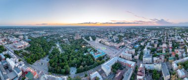 Yeşil bir lokomotif hurda metal yüklü bir treni limandaki tren istasyonuna çeker. Yeşil ve sarı yapraklı ağaçlar. Akşam sonbahar aydınlatması.
