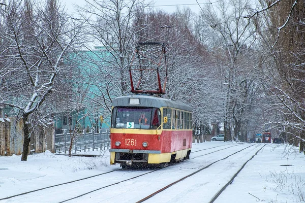 Dnipro, Ukrayna - Kış 2021: Kırmızı bir Tatra T3 tramvayı karlı bir cadde boyunca raylarda ilerliyor. Kentsel yolcu taşımacılığı.