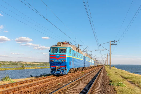 Zaporozhye, Ukrayna - 2021 Yazı: Güzel bir elektrikli lokomotif ChS7 uzun bir yolcu trenini denizden çeker. Yakın çekim görüntüsü. Akşam ışığı..