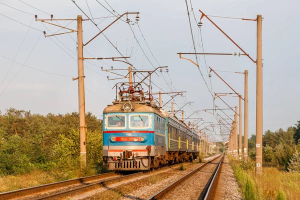 Dnipro, Ukrayna - Yaz 2020: Eski bir elektrikli lokomotif Skoda ChS2 yaz akşamı güneşinin altında banliyö yolcu trenini çekiyor. Ukrayna Demiryolu