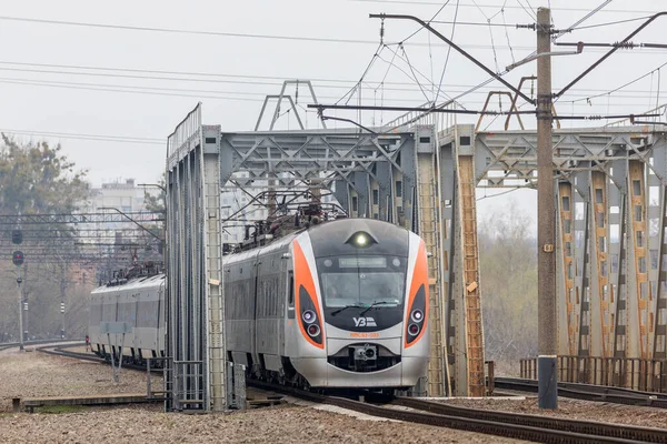 Kharkiv, Ukrayna - Nisan 2021: Kiev 'den gelen Yeni Hyundai HRCS2 yüksek hızlı elektrikli tren Intercity nehrin üzerinden geçiyor. Ukrayna demiryolları. Bulutlu. Yakın çekim görünümü.