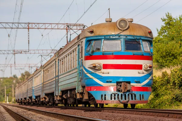 Eski bir banliyö elektrikli treni ER2 yaz güneşinin altında raylarda yol alır. Yakın çekim görüntüsü. Bokeh.