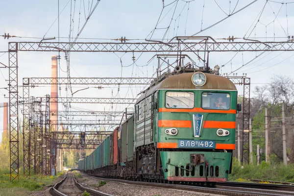 Dnipro, Ukrayna - 2021 Baharı: Güzel, nadir bulunan bir elektrikli lokomotif VL8, batan güneşin ışınlarıyla yüklü uzun bir yük trenini çekiyor. Ukrayna Demiryolu