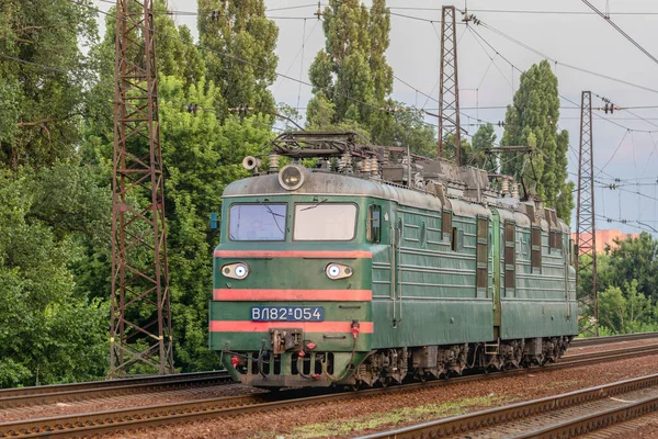 Kharkiv, Ukrayna - Yaz 2021: Eski bir yük elektrikli lokomotifi VL82 bir tren istasyonunun rayları boyunca farları açık olarak ilerliyor. Akşam ışığı.