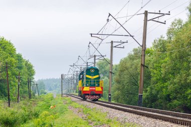 Lozova, Ukrayna - 2021 ilkbaharı: ChME3 lokomotifi yük vagonlarının arkasındaki tren istasyonuna tek bir hat üzerinde gidiyor. Bulutlu bahar havası. Ukrayna demiryolları.