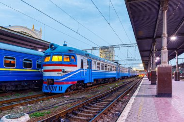 Tren istasyonunun kenarlarında çok arabalı bir yolcu elektrikli treni yer almaktadır. Banliyö yerel güzergahı. Gece aydınlatma.