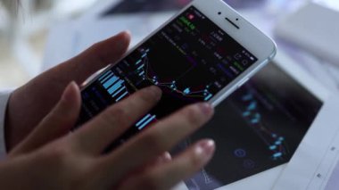 Borsa eğilimini incelemek için cep telefonunu ve düz ekran ekranı geçirin