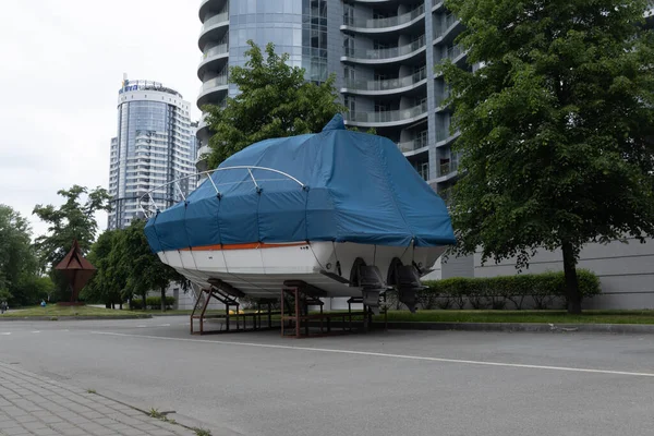 Mavi kapaklı bir motorlu tekne ağaçların arka planına karşı açık gökyüzünün altında duruyor..