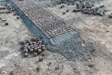 Taş kaldırım, inşaat işçisi kumlara taş döşeyen kaldırım taşları.