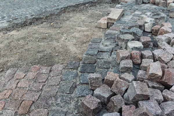 Taş kaldırım, inşaat işçisi kumlara taş döşeyen kaldırım taşları.