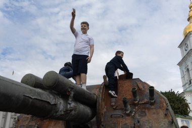 KYIV, UKRAINE - Haziran 06, 2022: Rus tankını Kyiv 'de yok etti ve yaktı. Çocuklar imha edilmiş bir tankla oynuyorlar..