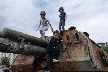 KYIV, UKRAINE - Haziran 06, 2022: Rus tankını Kyiv 'de yok etti ve yaktı. Çocuklar imha edilmiş bir tankla oynuyorlar..