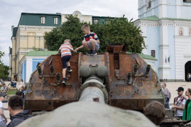 KYIV, UKRAINE - Haziran 06, 2022: Rus tankını Kyiv 'de yok etti ve yaktı. Çocuklar imha edilmiş bir tankla oynuyorlar..