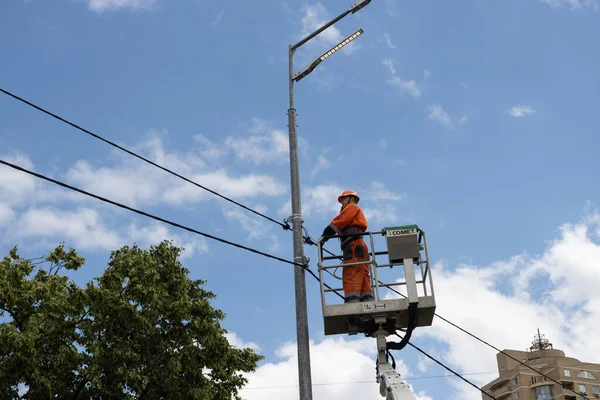 KYIV, UKRAINE - Haziran. 14, 2022: Özel bir kaldırma platformunda bir elektrikçi bir sokak lambasını tamir ediyor.