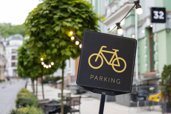 A black bicycle sign with a picture of yellow bike and text parking. Convenient infrastructure of big city streets. Parking area space for two-wheelers transport on the European street. Urban concept.