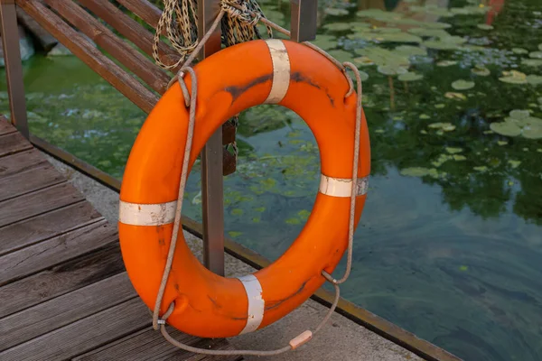 Old shabby lifebuoy on a wooden pier near the water.