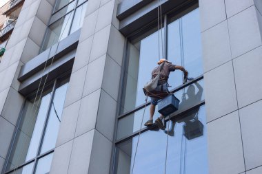 close up worker cleaning mirror in high bilding on sunset.