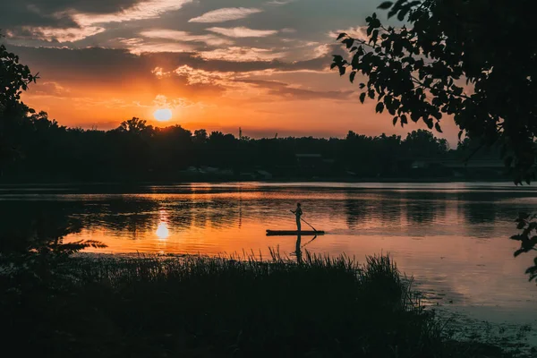 Silhouette image of a young girl on stand up paddle board in a river before sunset. Sup surfing.