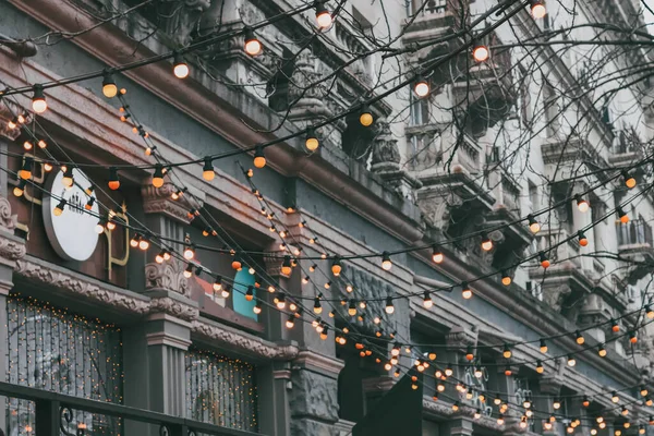 Sokaktaki yeni yıl çelenkleri eski bir Avrupa binasının arka planına karşı.