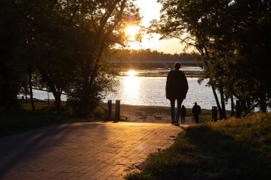 Nehirde gün batımı. Gün batımının arka planında, nehirde insanların siluetleri..