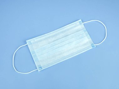 Mask protective coronavirus.Disposable surgical face mask top view on isolated blue background.