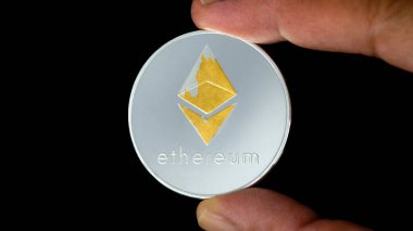 Ethereum - İzole edilmiş siyah arka planda ETH madeni para. Madeni para. Eth madeni para elinde. Elinizde şifreli sanal para var. İşsizlik, ticaret, değişim, dijital para.
