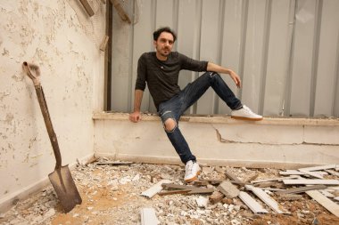 A man sits in a destroyed house