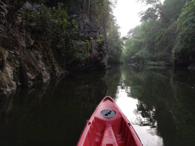 Nehirde kürek çeken kırmızı kanolar yazın Pha Hob, Mae Moh, Tayland 'da nehir kıyısında kürek çeken turist kanoları.