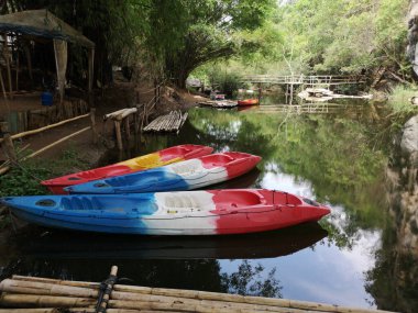 Nehirde kürek çeken kırmızı kanolar yazın Pha Hob, Mae Moh, Tayland 'da nehir kıyısında kürek çeken turist kanoları.
