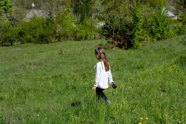 Küçük kız yeşil bir tarlada yürüyor. Arka plan