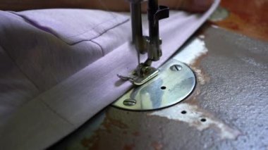 Seamstress sews on the old sewing machine close-up. The needle of the sewing machine makes a stitch with a thread. Sewing fabric on a sewing machine. High quality 4k footage