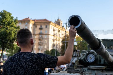Man touches the muzzle of a tank. Exhibition of Russian military equipment destroyed by the armed forces of Ukraine. High quality photo