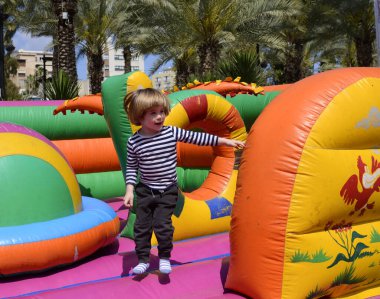 Çocuk renkli trambolinde atlıyor. Çocuklar anaokulundaki doğum günü partisinde şişme şatoya atlayıp küçük çocuklar için oyun merkezine giriyorlar. Küçük çocuk yazın dışarıda oynuyor..