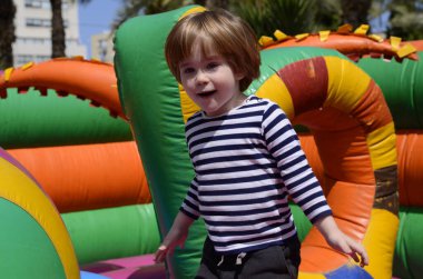 Çocuk renkli trambolinde atlıyor. Çocuklar anaokulundaki doğum günü partisinde şişme şatoya atlayıp küçük çocuklar için oyun merkezine giriyorlar. Küçük çocuk yazın dışarıda oynuyor..