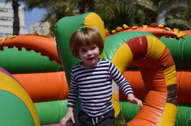 Çocuk renkli trambolinde atlıyor. Çocuklar anaokulundaki doğum günü partisinde şişme şatoya atlayıp küçük çocuklar için oyun merkezine giriyorlar. Küçük çocuk yazın dışarıda oynuyor..