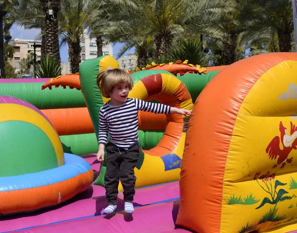 Çocuk renkli trambolinde atlıyor. Çocuklar anaokulundaki doğum günü partisinde şişme şatoya atlayıp küçük çocuklar için oyun merkezine giriyorlar. Küçük çocuk yazın dışarıda oynuyor..