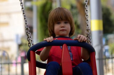 Küçük şirin çocuk parkta salıncakta sallanıyor. Çocuk gülüyor. yakın plan portre