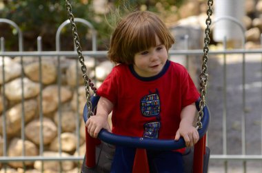 Küçük şirin çocuk parkta salıncakta sallanıyor. Çocuk gülüyor. yakın plan portre