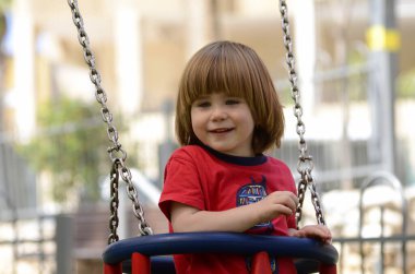 Küçük şirin çocuk parkta salıncakta sallanıyor. Çocuk gülüyor. yakın plan portre