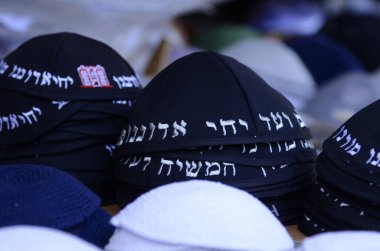 Geleneksel siyah Yahudi kipa kazıkları. Kippah 'ın sözleri pazarda satılmak için dua ediyor. Tanrı bizim Tanrımızdır, Tanrı tektir.